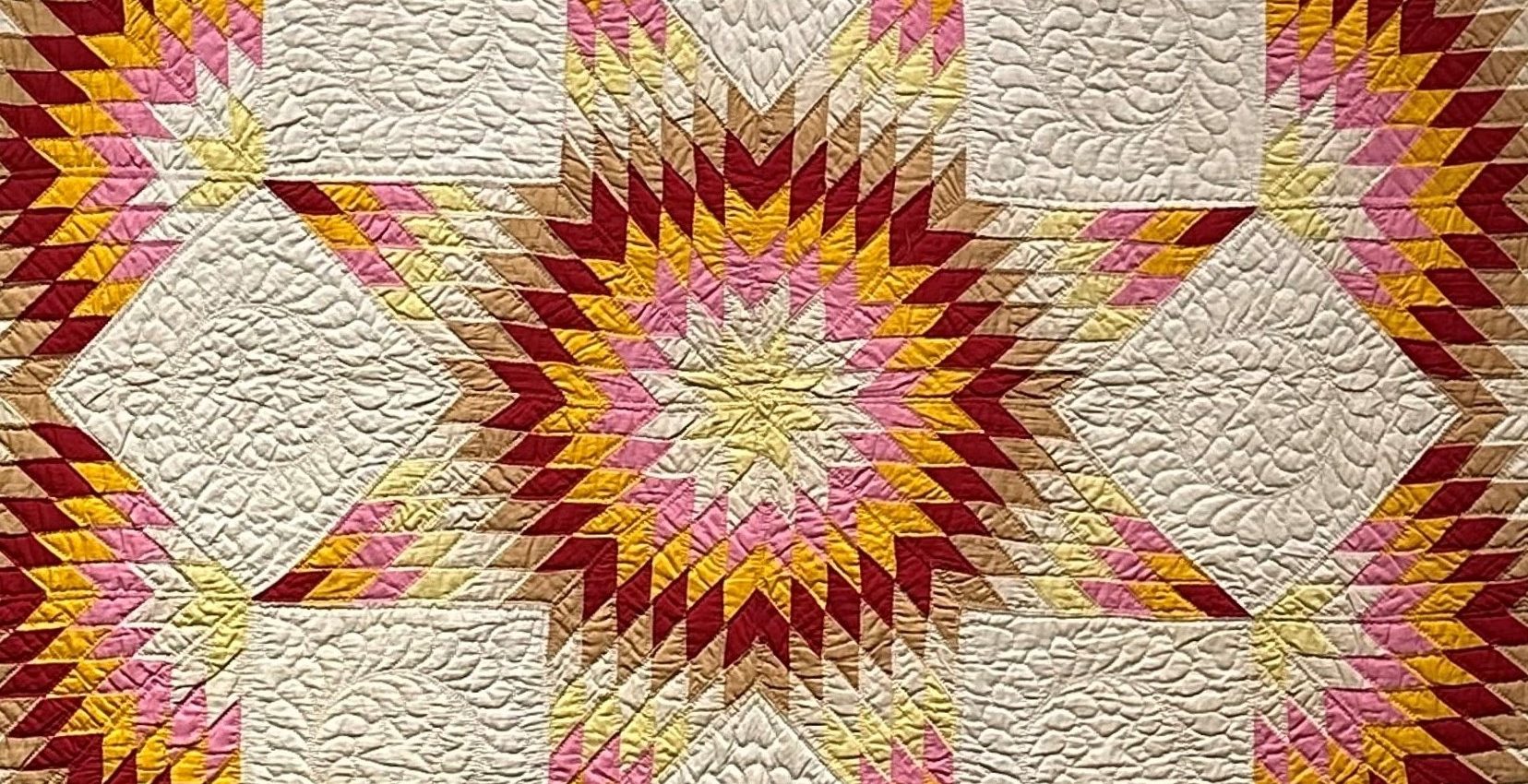 A quilt with a red, yellow and pink design.