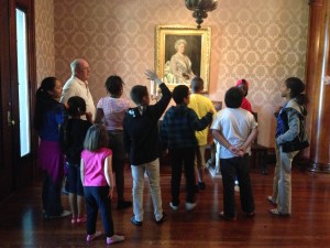 A group of children looking at a painting in a room.