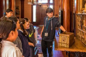A group of children are looking at an ornate box in a room.
