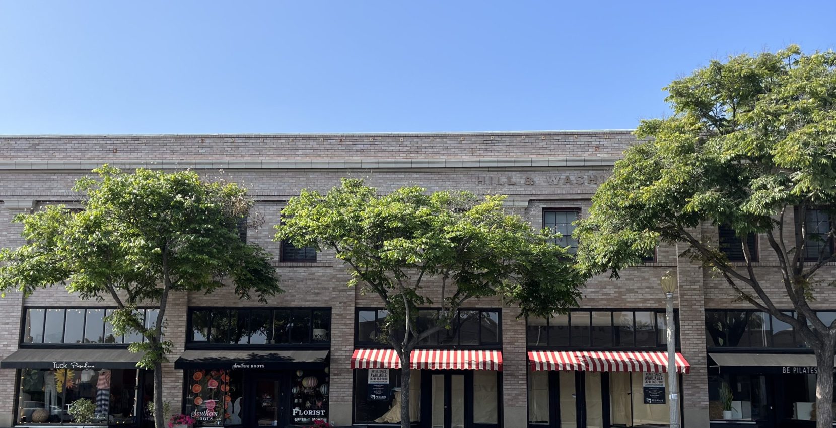 The front of a building with trees and awnings.