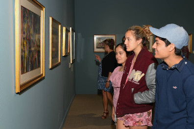 A group of people looking at paintings in a museum.