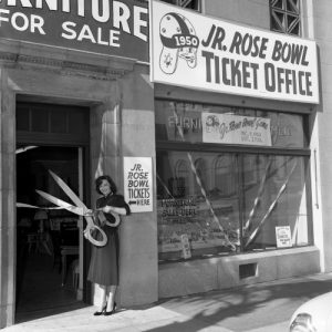 A woman holding scissors in front of a store.