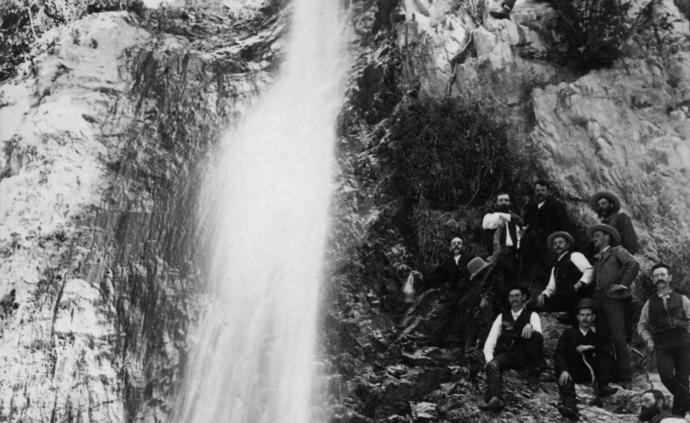 A group of people sitting on the side of a waterfall.