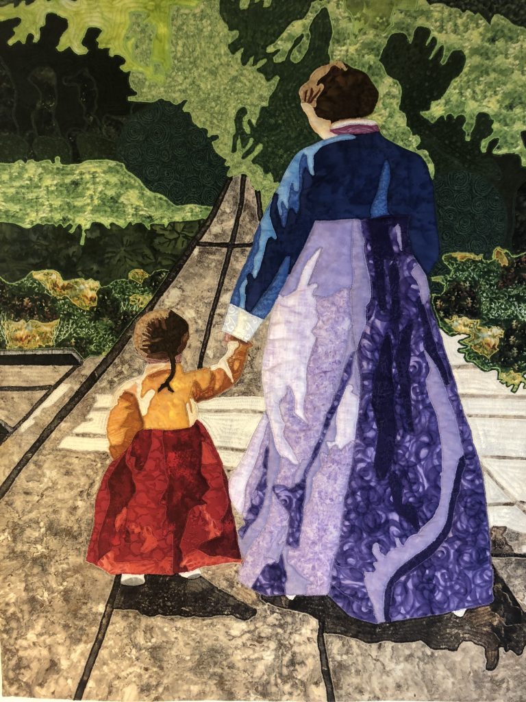 a quilt depicting a mother and child walking in a garden