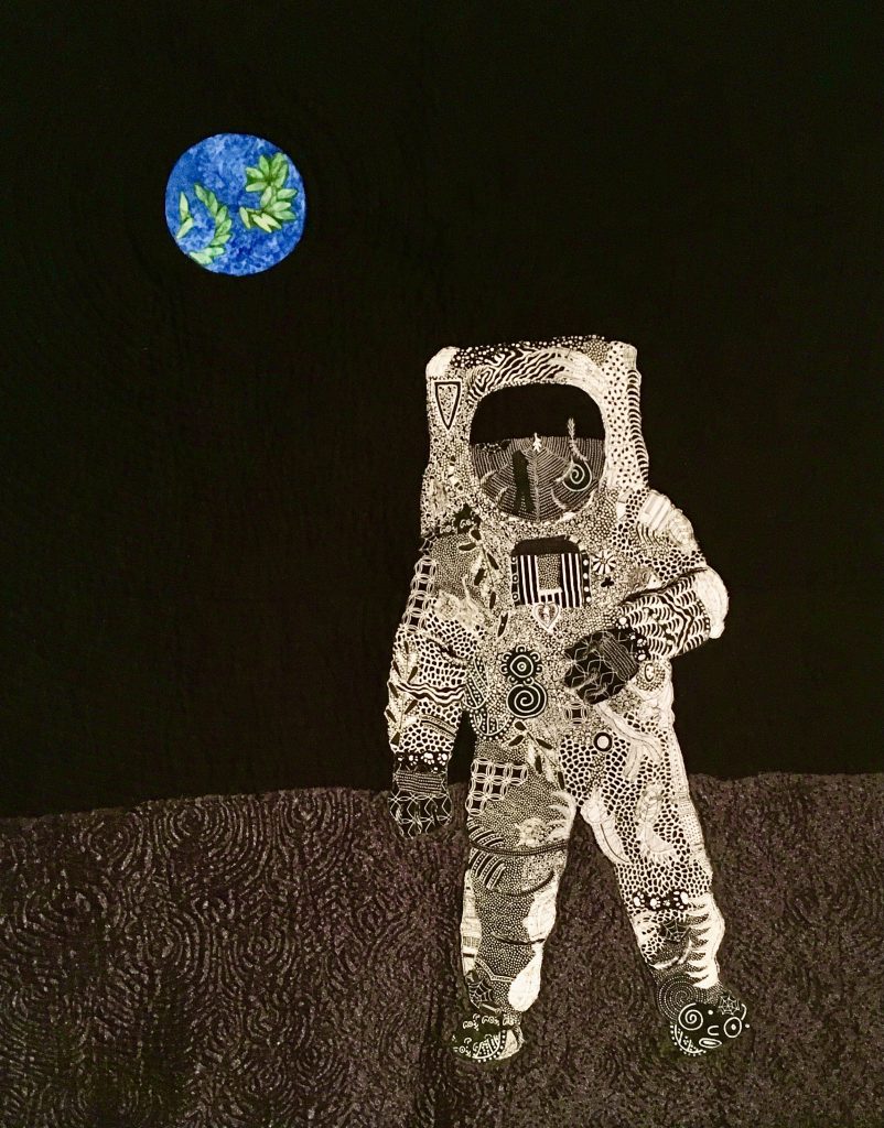 A quilt depicting an astronaut and planet Earth