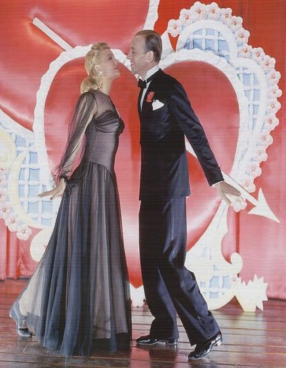 Fred Astaire and Marjorie Reynolds Kissing in front of a large Valentines Day heart